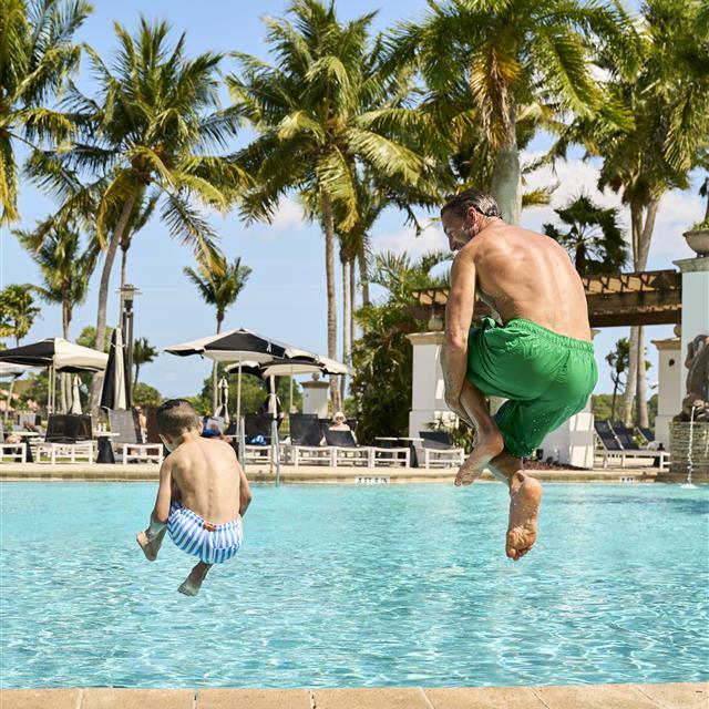 Father and son cannonball into pool